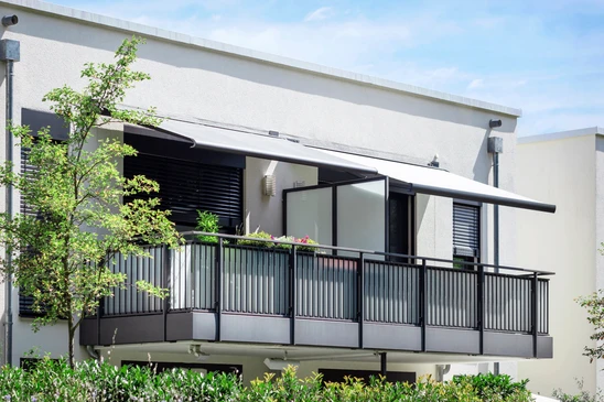 Terrasse extérieure d'appartement avec store banne beige déployé offrant protection solaire