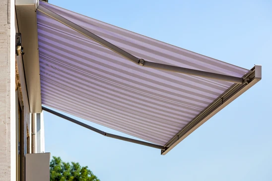 Jardin contemporain avec terrasse en bois exotique, mobilier design empilable noir, voile d'ombrage triangulaire beige tendue au-dessus