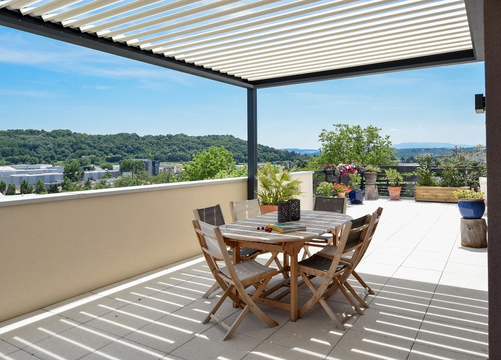 Pergola bioclimatique aluminium laqué gris, structure autoportante à toiture plate avec lames orientables