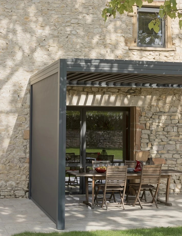Pergola bioclimatique vue de dessous, lames orientables en aluminium blanc partiellement ouvertes, structure portante en aluminium anthracite