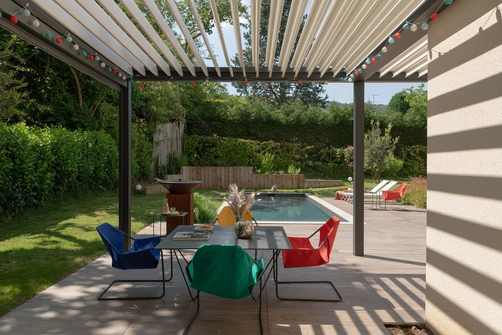 Terrasse extérieure couverte d'une pergola bioclimatique à lames orientables en aluminium blanc