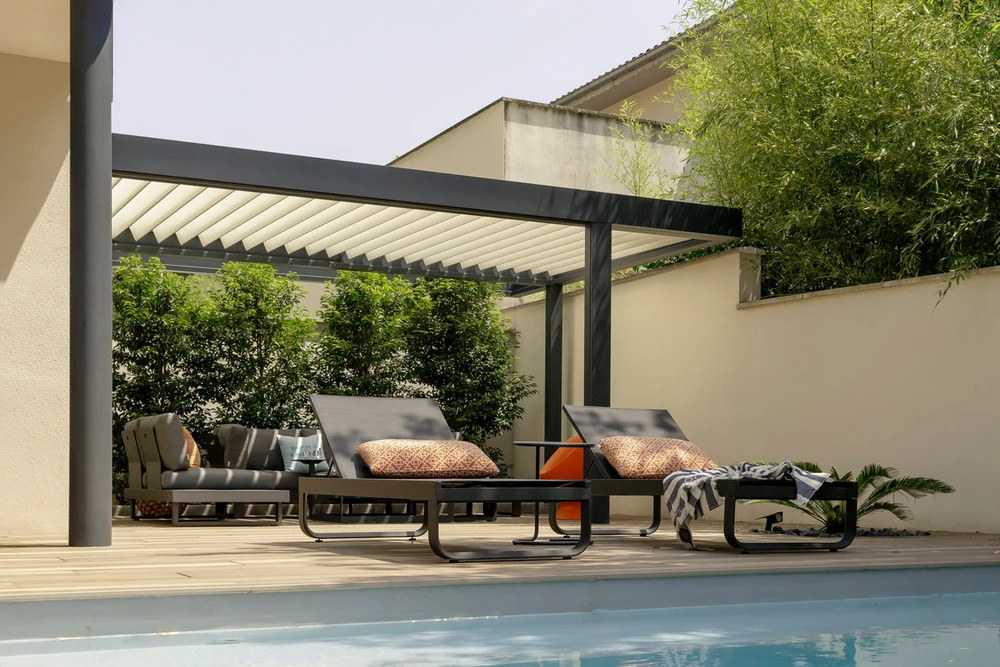 Pergola bioclimatique aluminium laqué gris, structure autoportante à toiture plate avec lames orientables