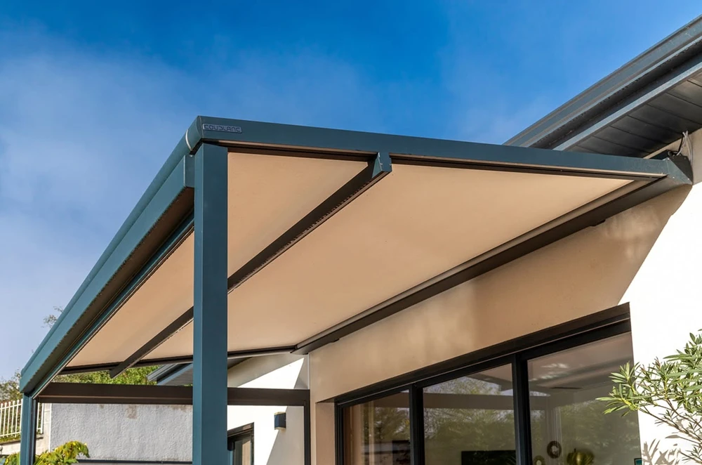 Terrasse urbaine couverte d'une pergola bioclimatique à lames orientables en aluminium anthracite, fermée par une toile screen latérale beige