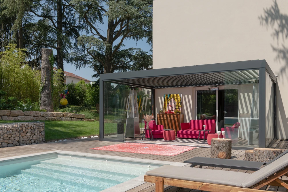 Pergola bioclimatique à lames orientables en aluminium anthracite, structure autoportante fixée en façade d'une maison contemporaine