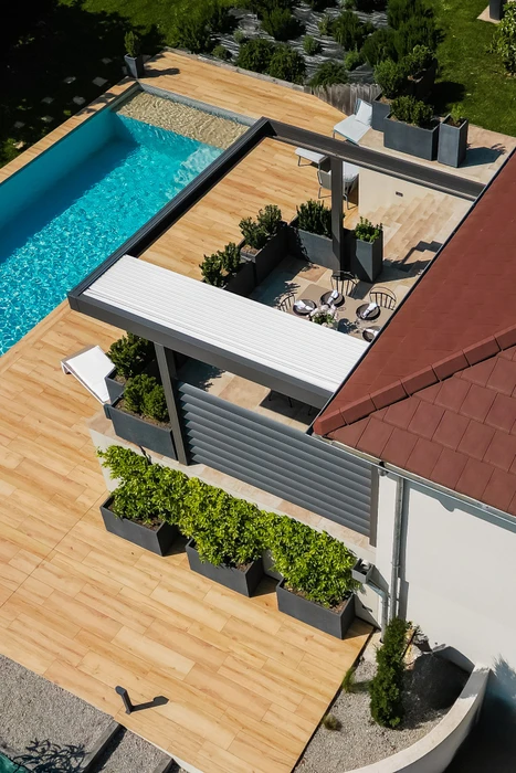Pergola bioclimatique en aluminium anthracite avec lames orientables horizontales en position semi-ouverte, constituant un claustra latéral