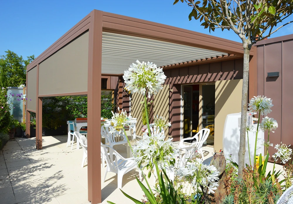 Pergola bioclimatique à lames orientables en aluminium anthracite, structure autoportante fixée en façade d'une maison contemporaine