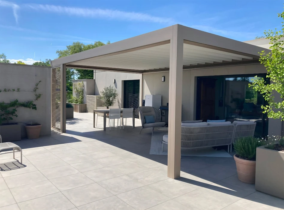 Pergola bioclimatique à lames orientables en aluminium anthracite, structure autoportante fixée en façade d'une maison contemporaine