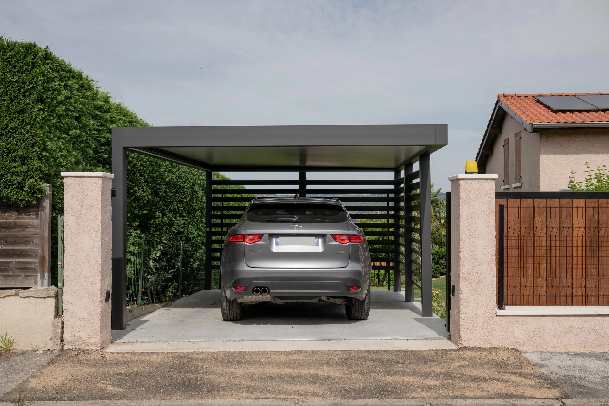 Espace extérieur couvert avec structure métallique noire supportant une toiture plate