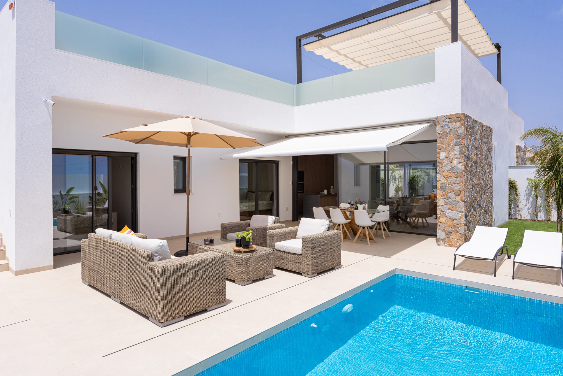 Terrasse extérieure équipée de stores enrouleurs pare-soleil gris semi-transparents suspendus à une structure métallique